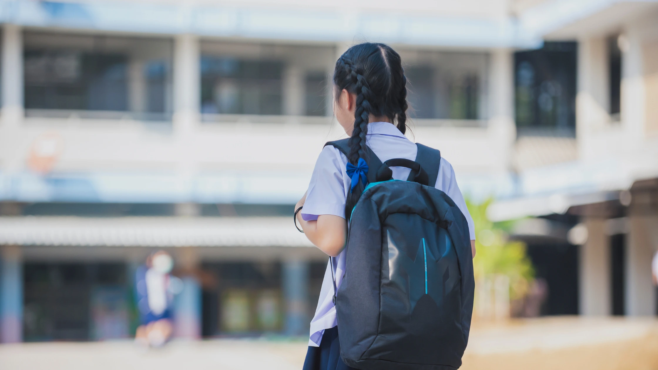 A school student carrying a backpack on the school campus.